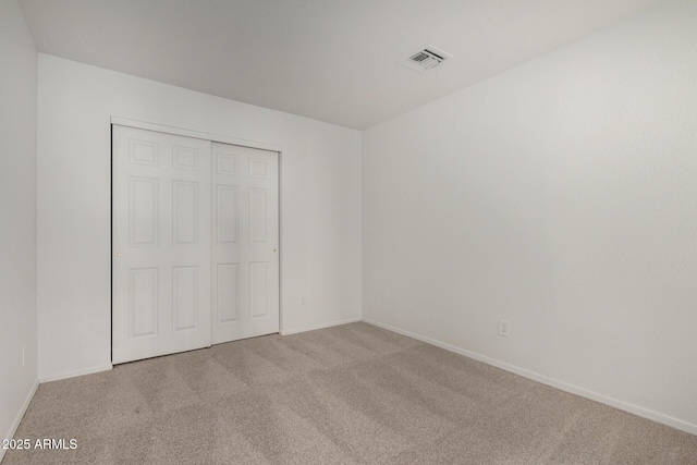 unfurnished bedroom featuring carpet floors, baseboards, visible vents, and a closet