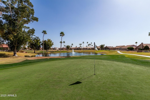 view of home's community with a water view, golf course view, and a yard