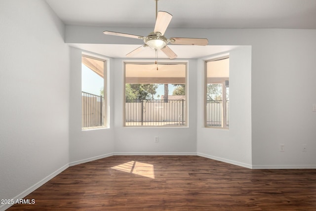 spare room featuring dark wood-style floors, ceiling fan, and baseboards