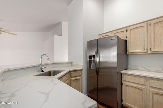 kitchen featuring a ceiling fan, light stone countertops, light brown cabinets, stainless steel refrigerator with ice dispenser, and a sink