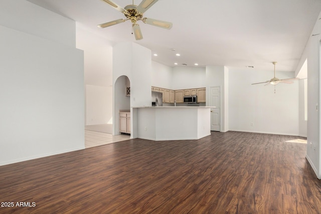 unfurnished living room featuring arched walkways, recessed lighting, ceiling fan, wood finished floors, and baseboards