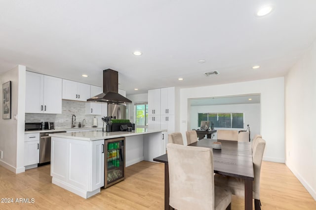 kitchen featuring a center island, wine cooler, stainless steel dishwasher, white cabinetry, and extractor fan