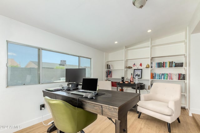 home office with built in features, light wood-type flooring, and lofted ceiling