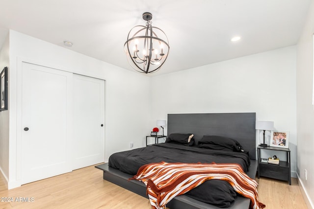 bedroom with a notable chandelier, light wood-type flooring, and a closet