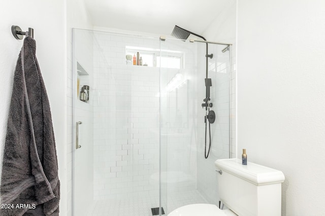 bathroom with a shower with shower door and toilet