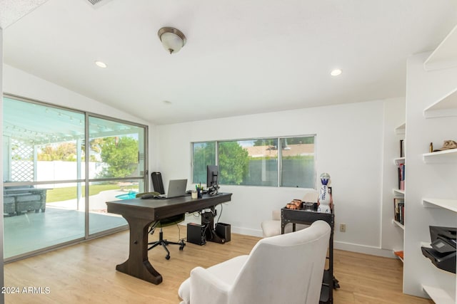 office space featuring built in shelves, a healthy amount of sunlight, light hardwood / wood-style floors, and vaulted ceiling