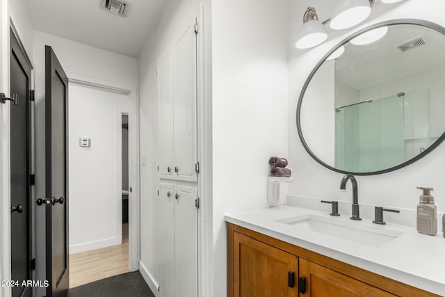 bathroom with a shower with door and vanity