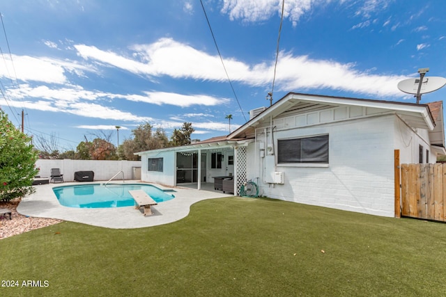 back of property with a patio, a fenced in pool, and a lawn