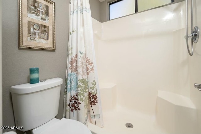 bathroom with toilet and a shower with shower curtain