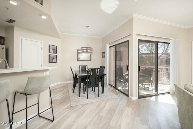 dining space featuring ornamental molding and light hardwood / wood-style floors