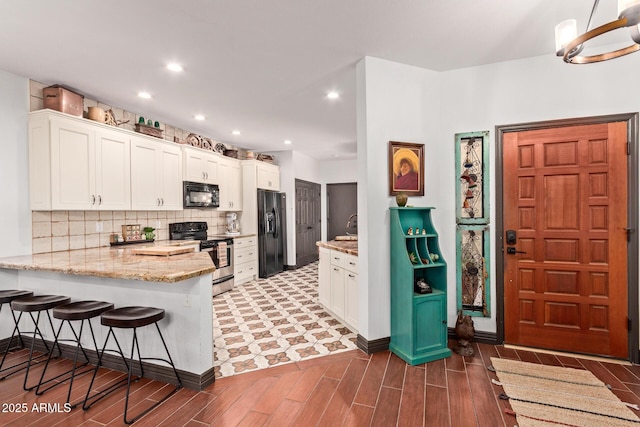 1235 N Sunnyvale Unit 113, Mesa, AZ 85205 - kitchen featuring black appliances, a peninsula, wood tiled floors, white cabinetry, and a breakfast bar