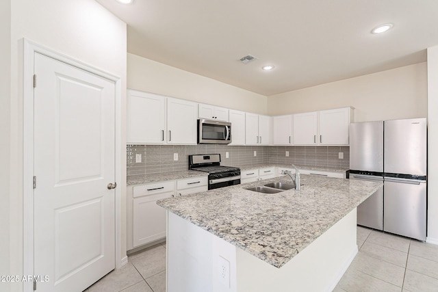 kitchen featuring light tile patterned floors, stainless steel appliances, a sink, visible vents, and decorative backsplash