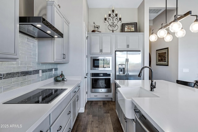 kitchen with white cabinetry, wall chimney exhaust hood, dark wood-type flooring, stainless steel appliances, and decorative light fixtures