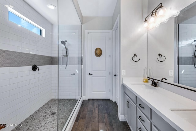 bathroom with tiled shower, wood-type flooring, and vanity