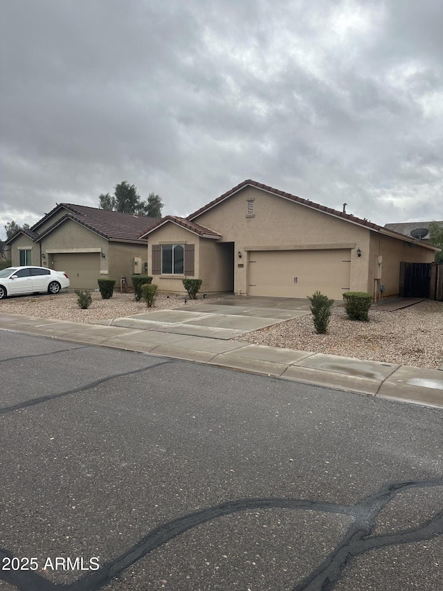 ranch-style house featuring stucco siding, driveway, and an attached garage