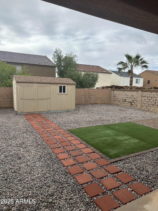 view of yard with an outbuilding, a storage shed, and a fenced backyard