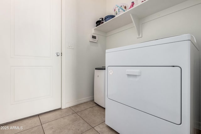 washroom with light tile patterned flooring, laundry area, washer / dryer, and baseboards