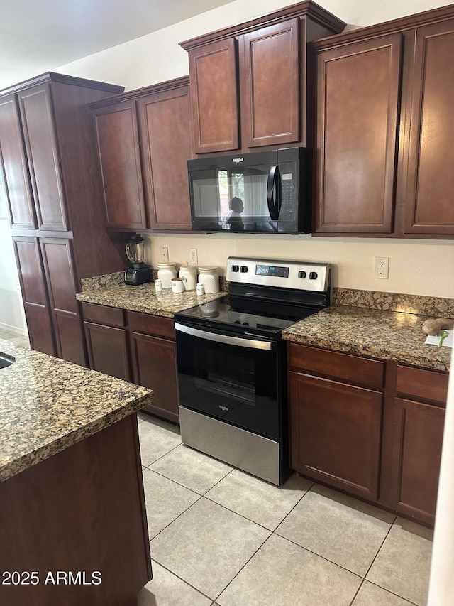 kitchen with dark stone countertops, light tile patterned floors, electric stove, and black microwave