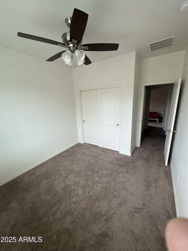 unfurnished bedroom with a closet, visible vents, baseboards, and dark colored carpet