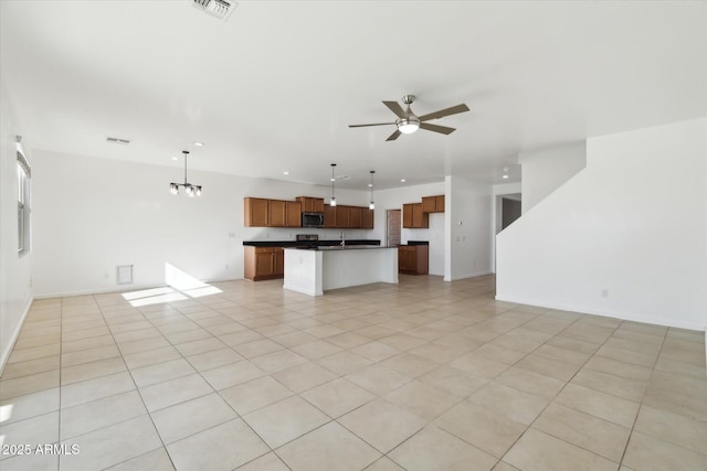 unfurnished living room with ceiling fan with notable chandelier and light tile patterned floors