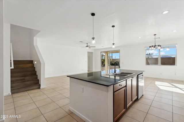 kitchen with sink, light tile patterned floors, decorative light fixtures, and an island with sink