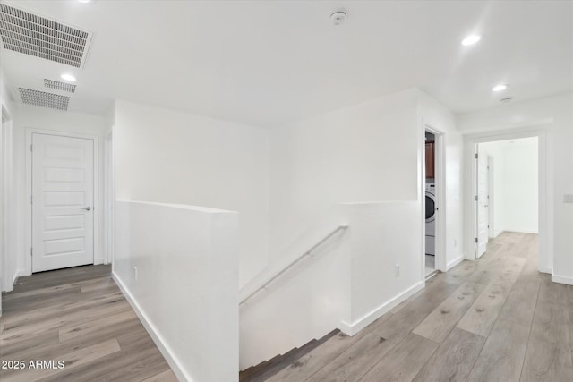 corridor with washer / dryer and light wood-type flooring