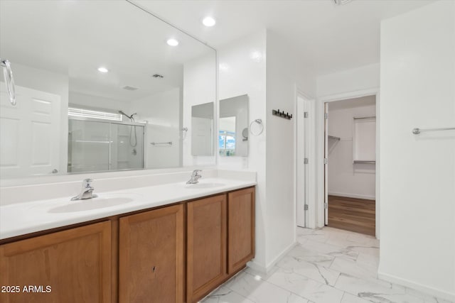 bathroom featuring a shower with door and vanity