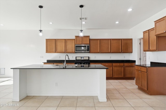 kitchen with pendant lighting, sink, stainless steel appliances, and an island with sink