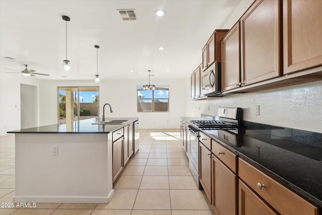 kitchen with sink, an island with sink, a wealth of natural light, pendant lighting, and stainless steel appliances