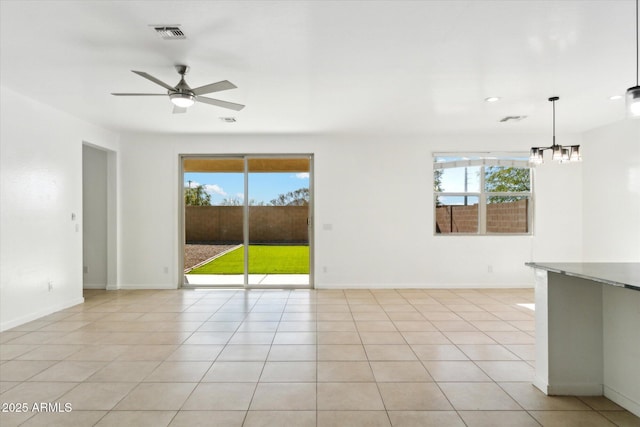 unfurnished room with ceiling fan with notable chandelier and light tile patterned flooring