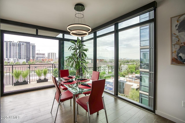 dining space with floor to ceiling windows, plenty of natural light, a view of city, and wood finished floors