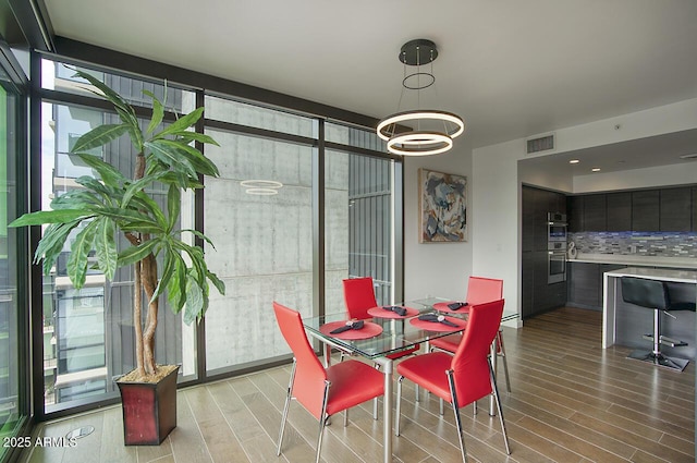 dining area featuring light wood-style flooring, visible vents, and an inviting chandelier
