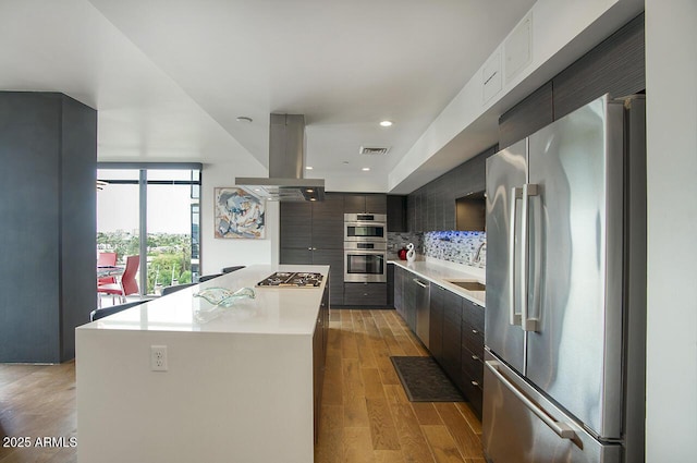 kitchen with a kitchen island, light wood-type flooring, stainless steel appliances, island exhaust hood, and visible vents
