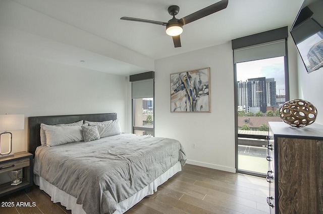 bedroom with multiple windows, wood finished floors, baseboards, and access to outside