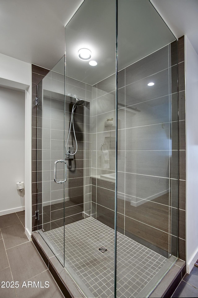 full bathroom with tile patterned floors, baseboards, and a shower stall