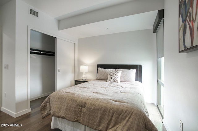 bedroom featuring wood finished floors, baseboards, a closet, and visible vents
