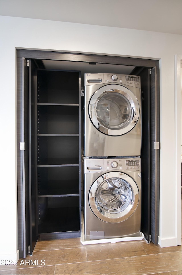 washroom featuring stacked washer and dryer, wood finished floors, and laundry area