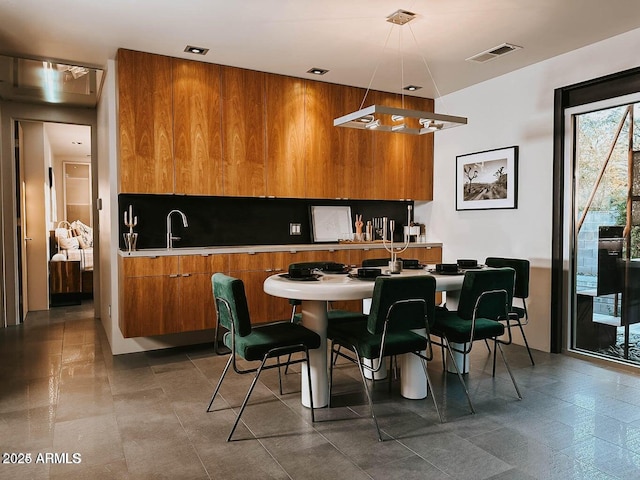 kitchen with brown cabinets, light countertops, visible vents, a sink, and modern cabinets