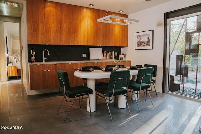 kitchen featuring modern cabinets, brown cabinets, a kitchen breakfast bar, hanging light fixtures, and light countertops