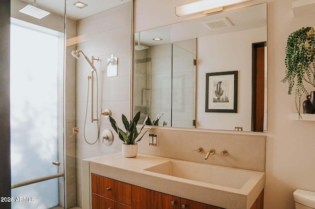 full bathroom featuring toilet, tiled shower, and vanity