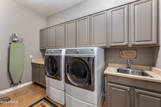 laundry area with washer and clothes dryer, light tile patterned flooring, cabinets, and sink