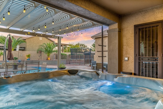 pool at dusk with a trampoline, a pergola, and a hot tub