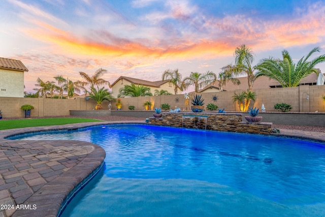 pool at dusk featuring pool water feature