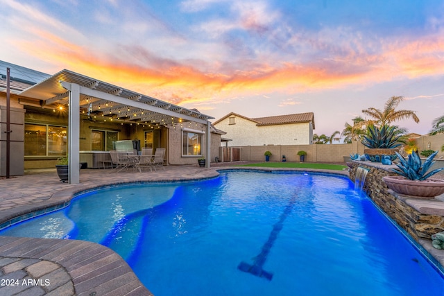 pool at dusk featuring a pergola, pool water feature, and a patio area