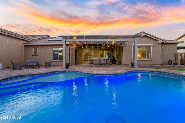 pool at dusk featuring a pergola and a patio area