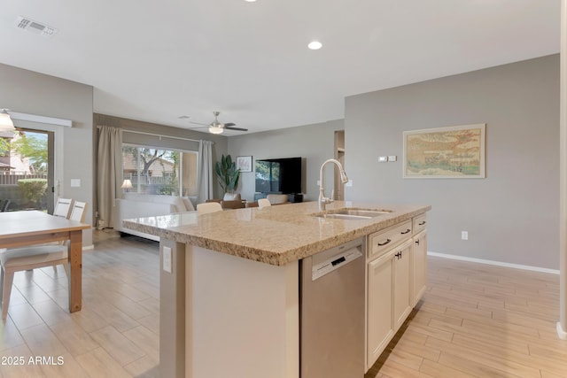 kitchen featuring visible vents, light stone countertops, dishwasher, a sink, and open floor plan