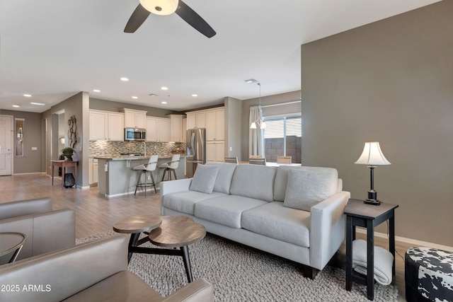 living area with baseboards, recessed lighting, light wood finished floors, and ceiling fan