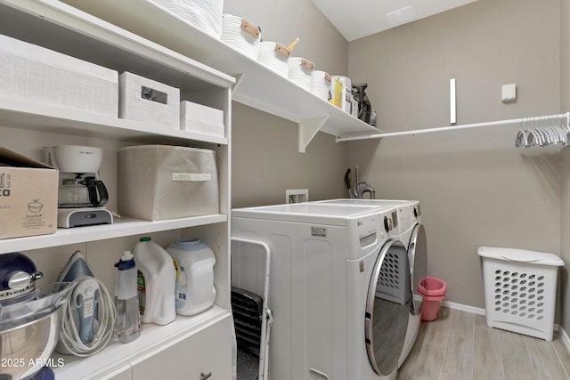 clothes washing area with baseboards, laundry area, light wood finished floors, and independent washer and dryer