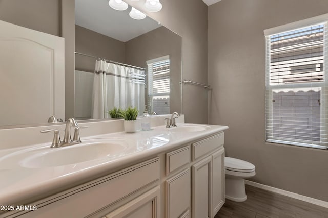 bathroom featuring toilet, baseboards, a sink, and wood finished floors