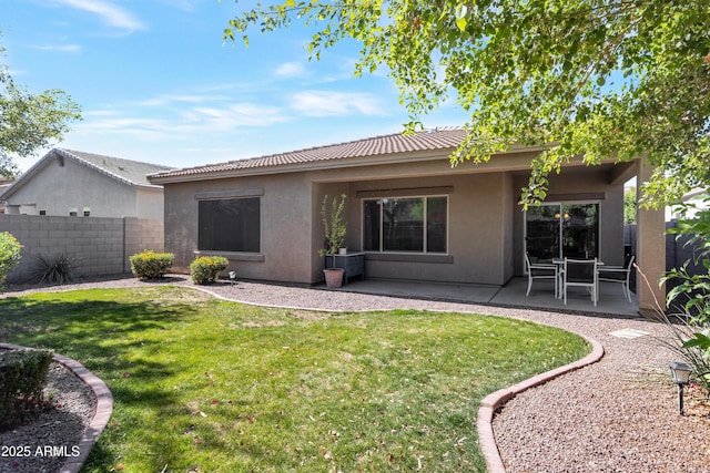 back of house featuring fence, stucco siding, a lawn, and a patio area